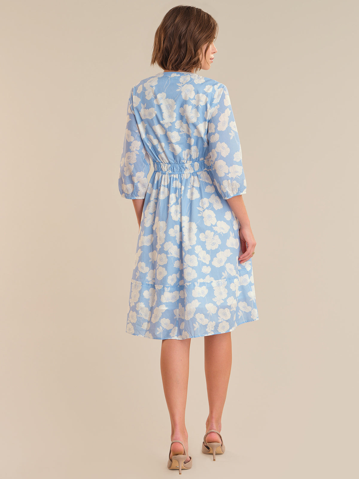 Woman wearing a blue floral dress on a beige background