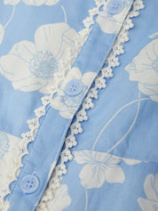 Close-up of a blue floral fabric with white lace trim and buttons.