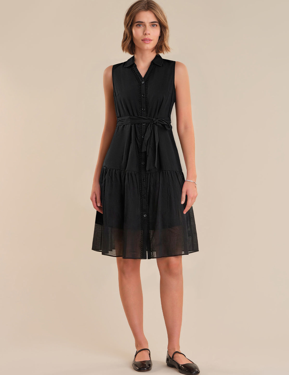 Woman wearing a black sleeveless dress on a beige background