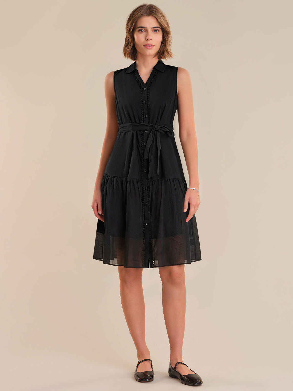 Woman wearing a black sleeveless dress on a beige background