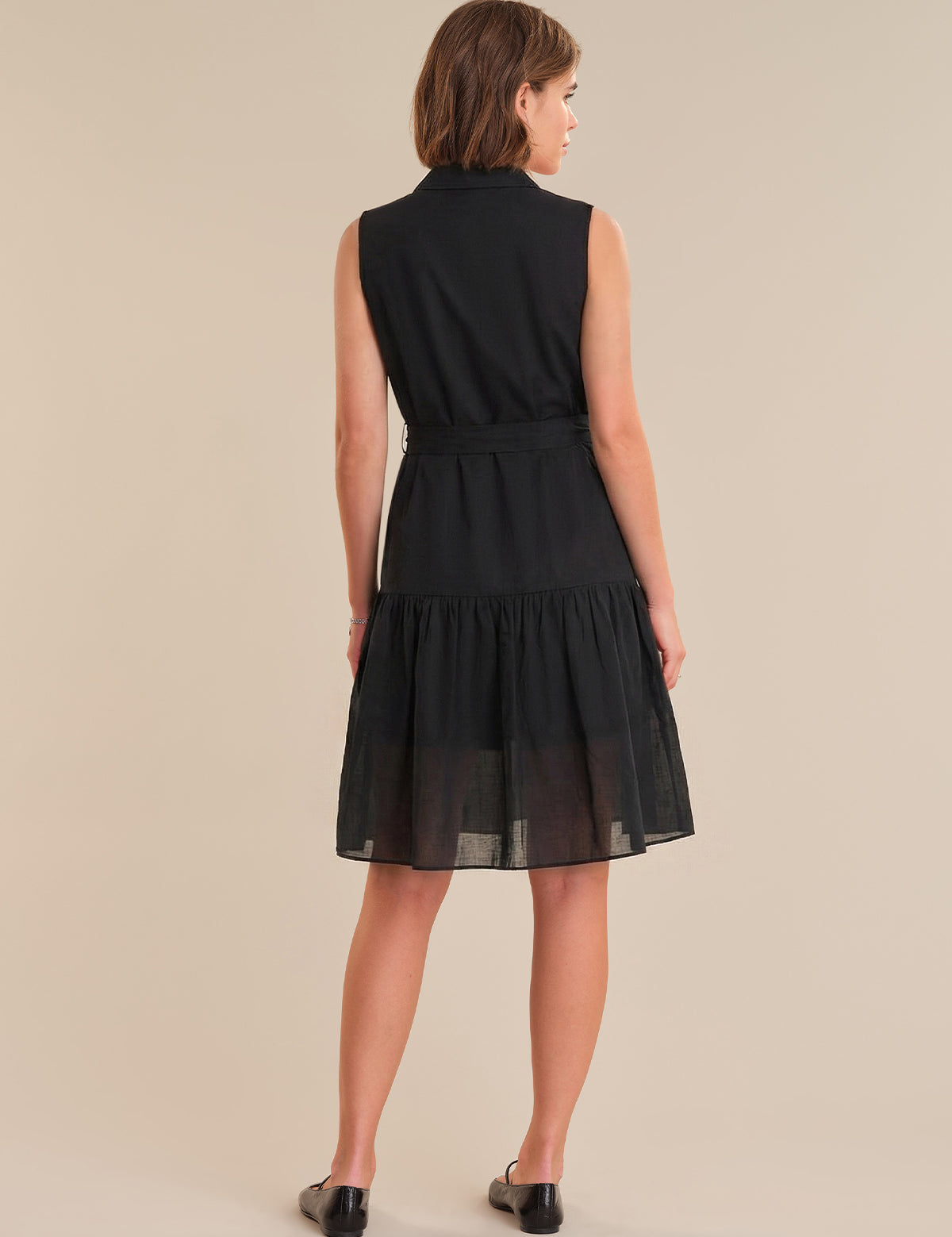 Woman wearing a black dress against a beige background