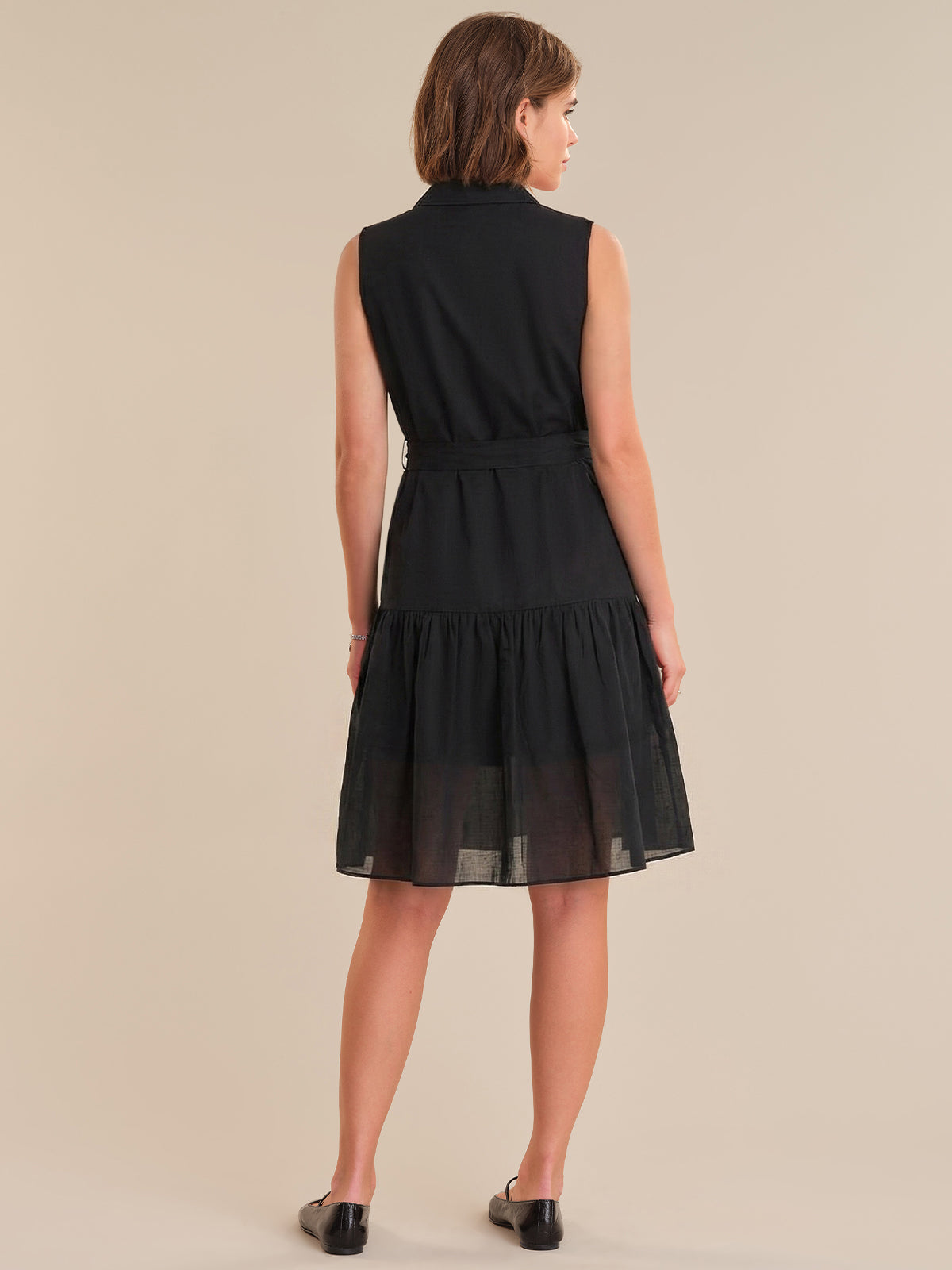 Woman wearing a black dress against a beige background