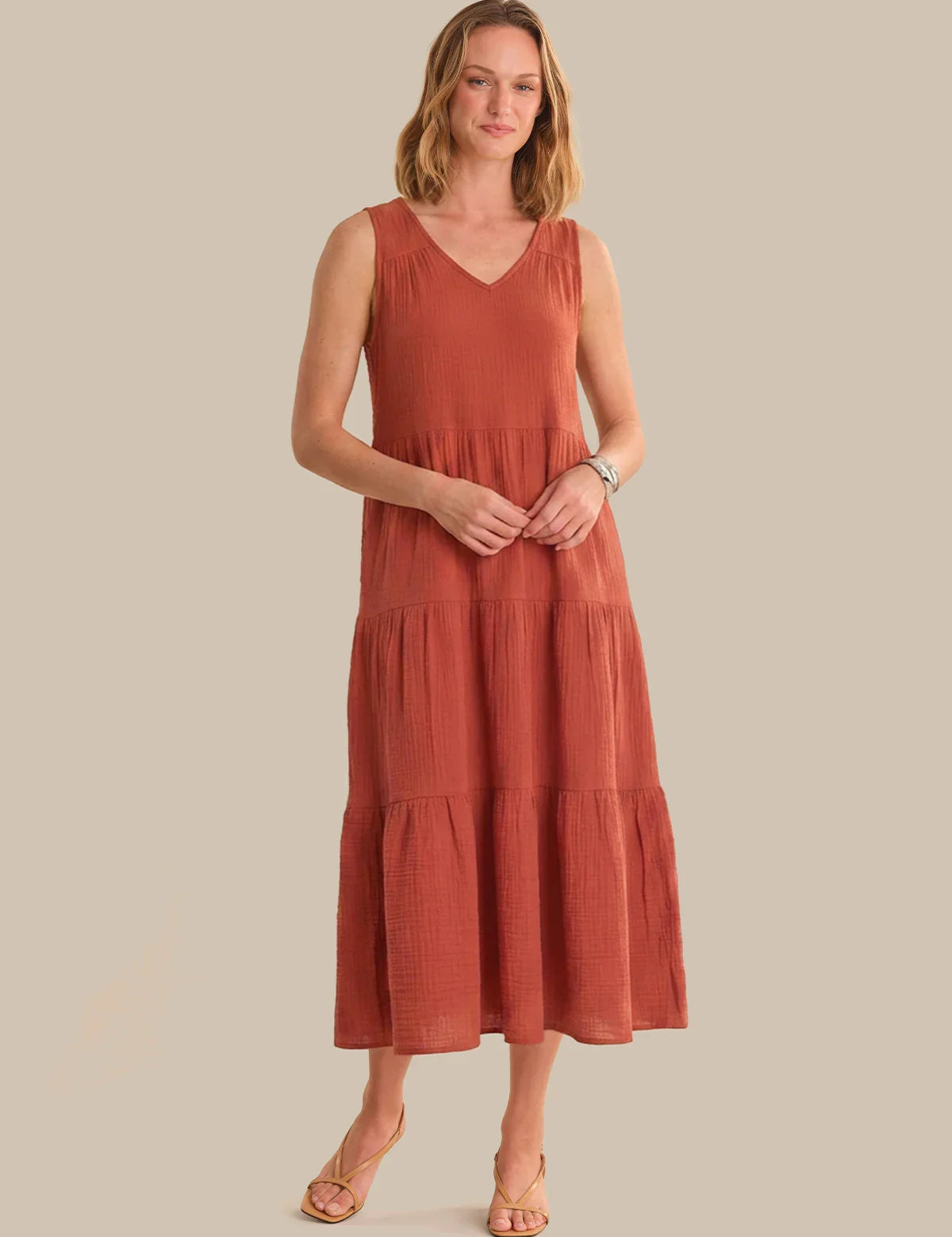Woman wearing a rust-colored dress against a plain background