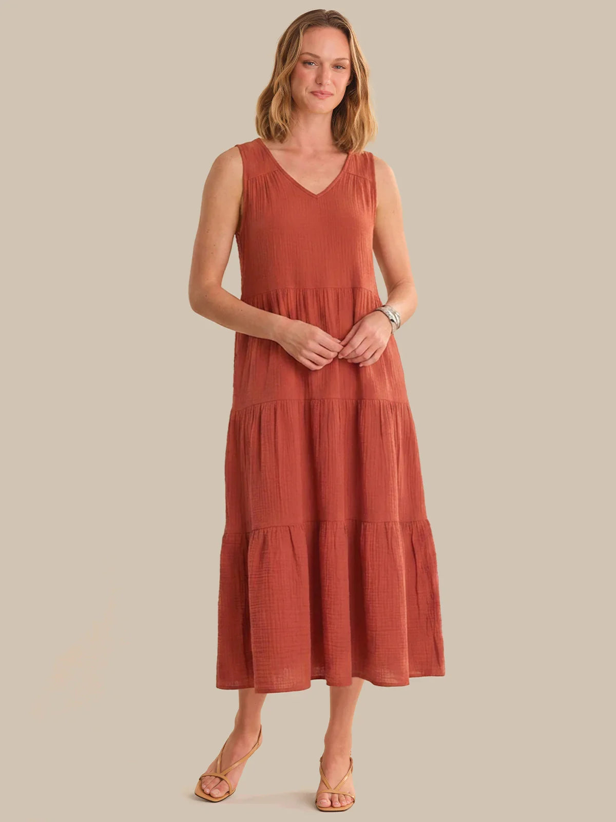 Woman wearing a rust-colored dress against a plain background