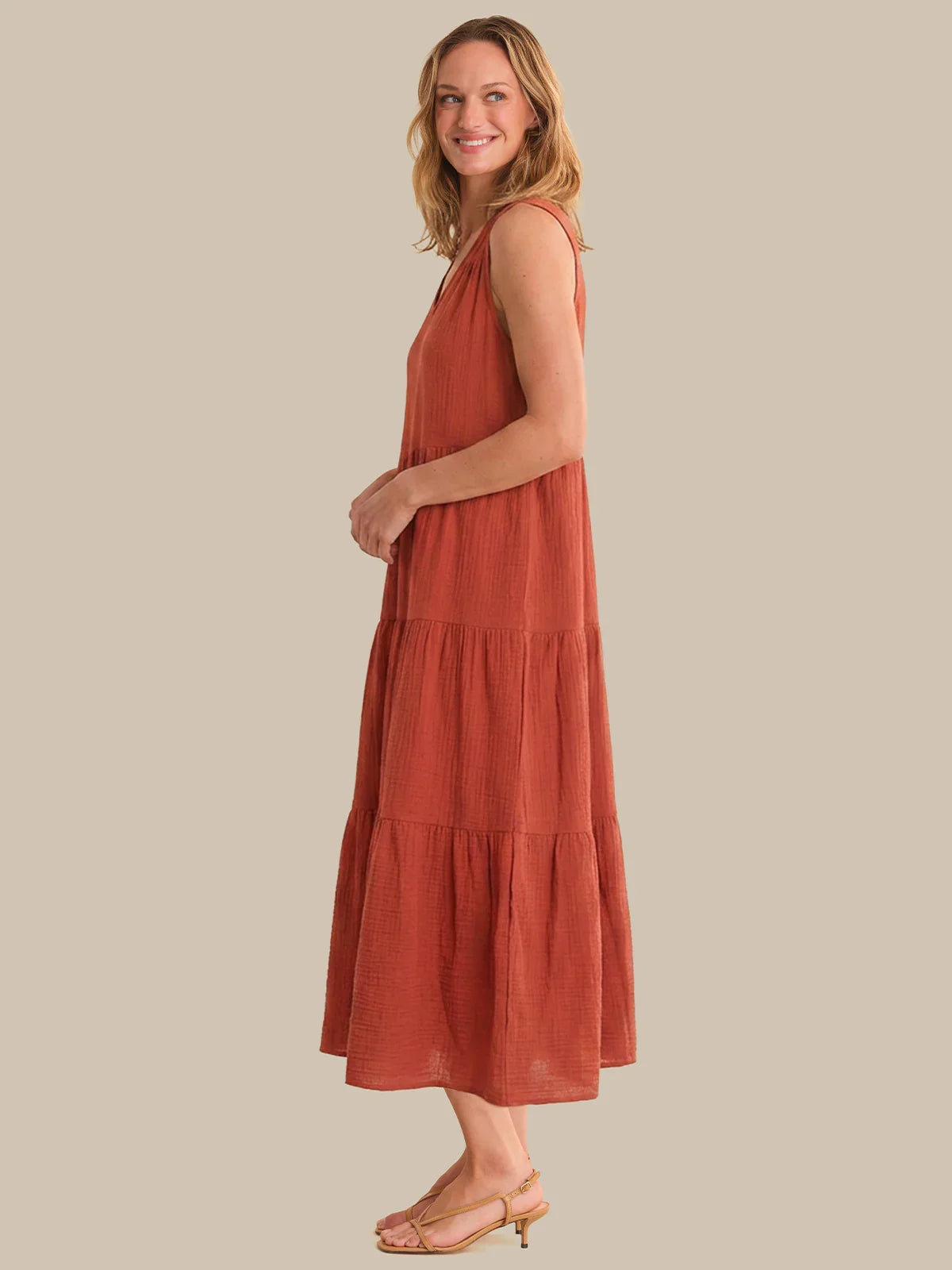 Woman wearing a rust-colored dress against a beige background