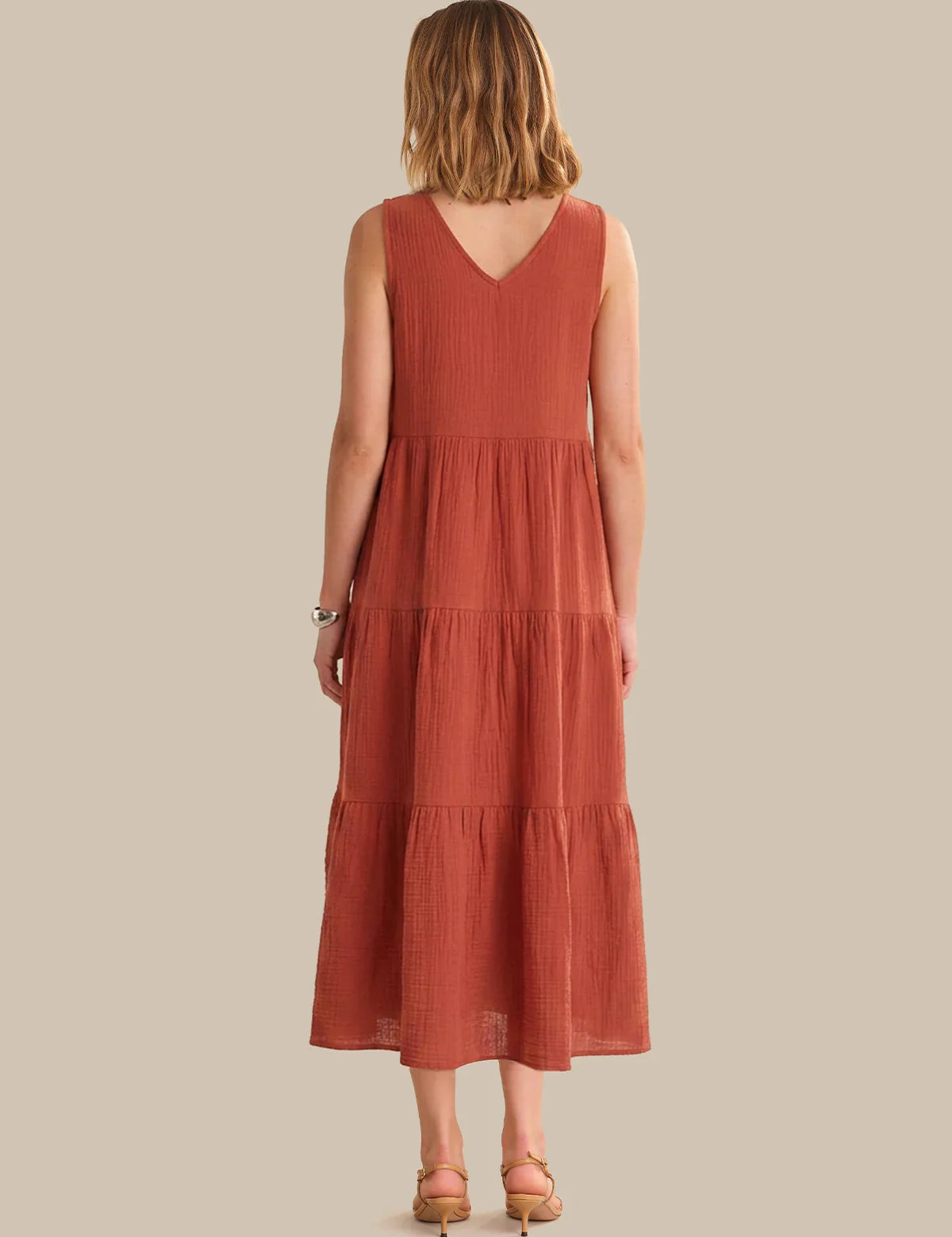Woman wearing a rust-colored dress with a plain background