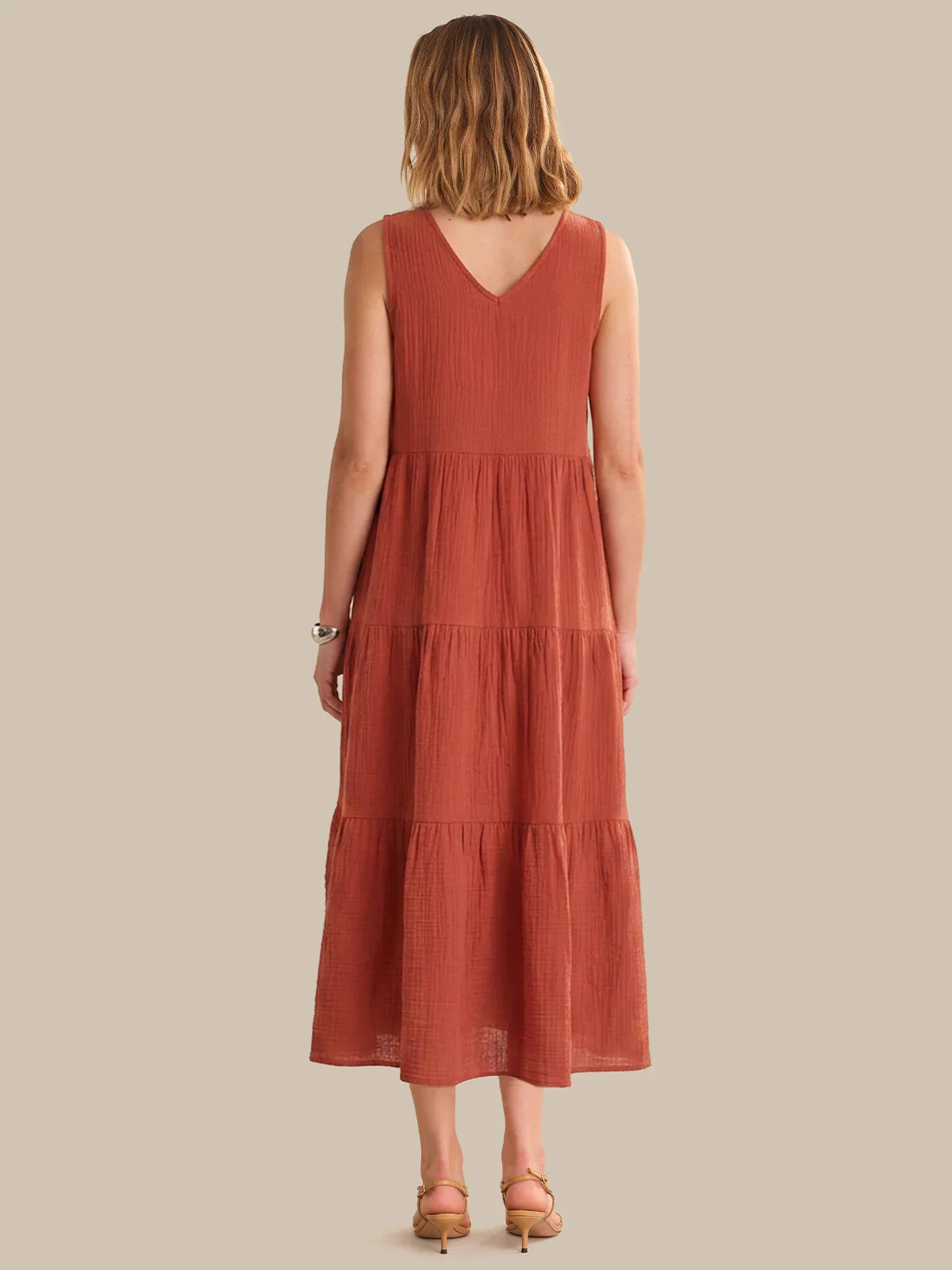 Woman wearing a rust-colored dress with a plain background