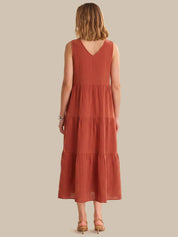 Woman wearing a rust-colored dress with a plain background