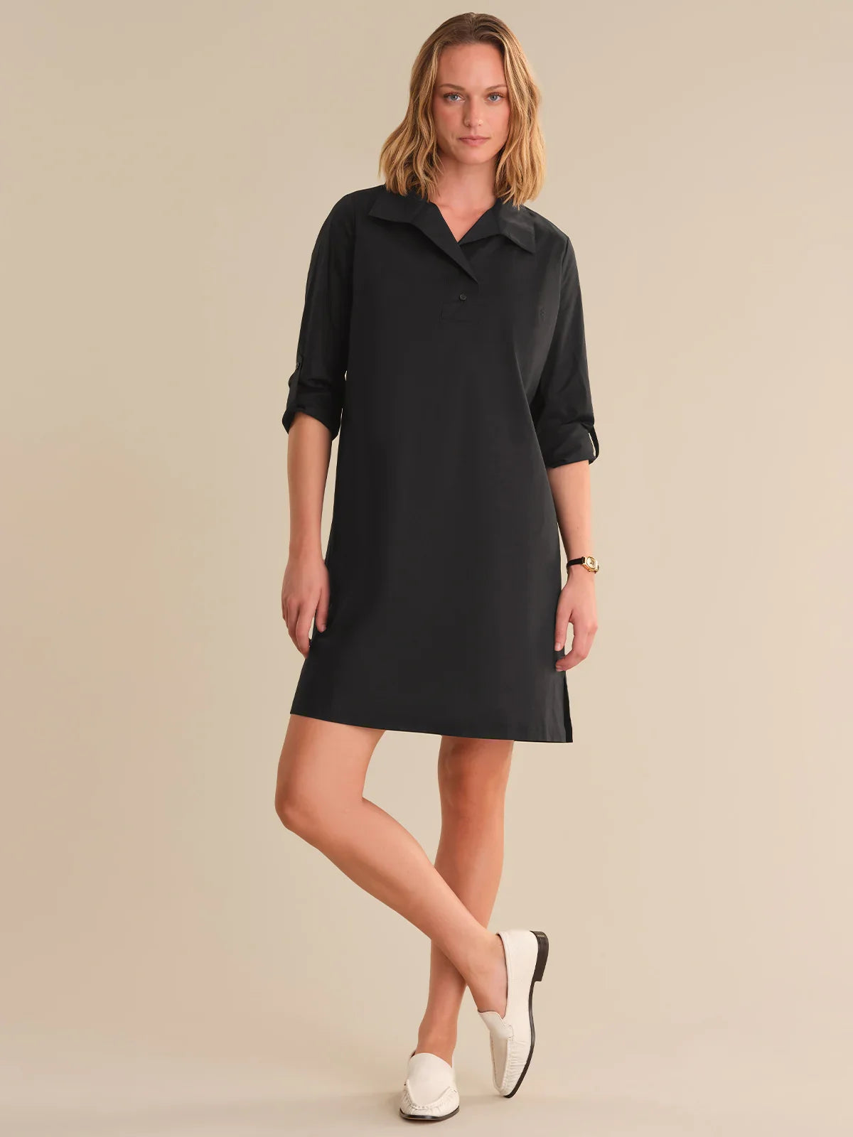 Woman wearing a black dress with a collar on a beige background
