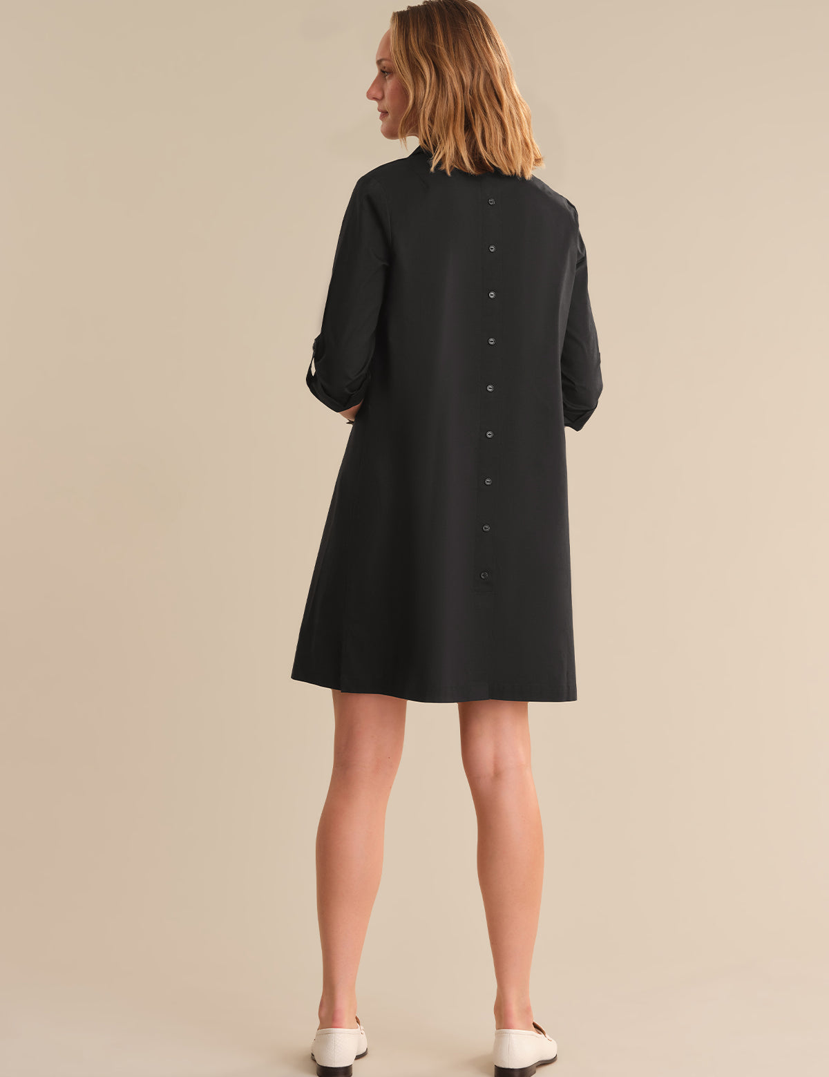 Woman wearing a black dress against a beige background