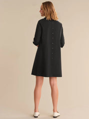 Woman wearing a black dress against a beige background