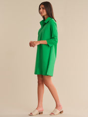 Woman wearing a green dress against a beige background