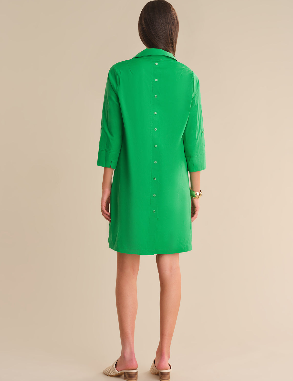 Green dress worn by a person on a beige background