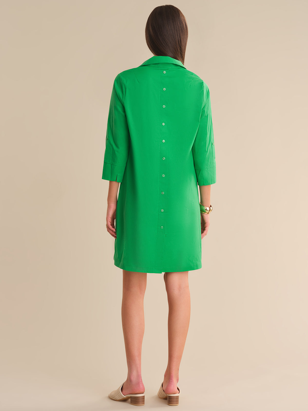 Green dress worn by a person on a beige background