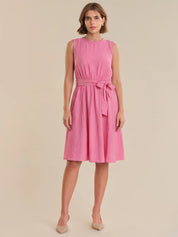 Woman wearing a pink dress with a belt on a beige background