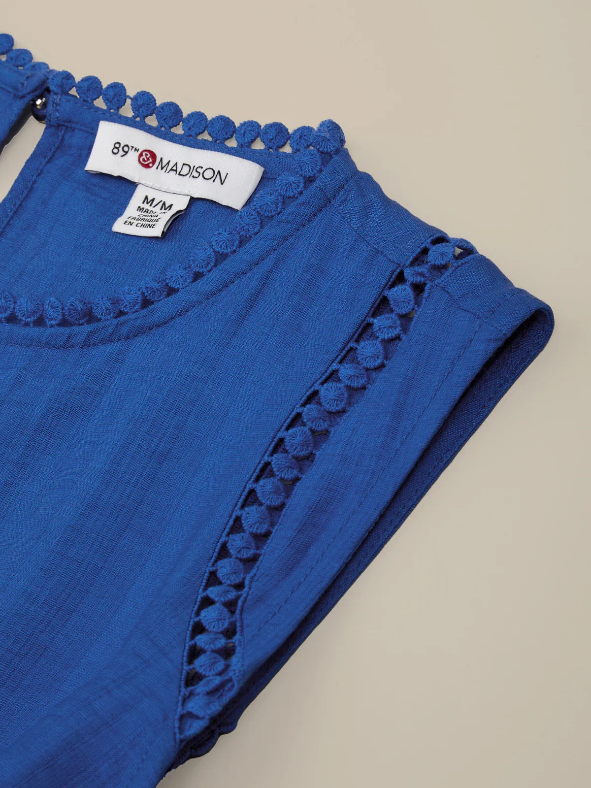 Blue garment with lace trim and '89TH Madison' label on a beige background