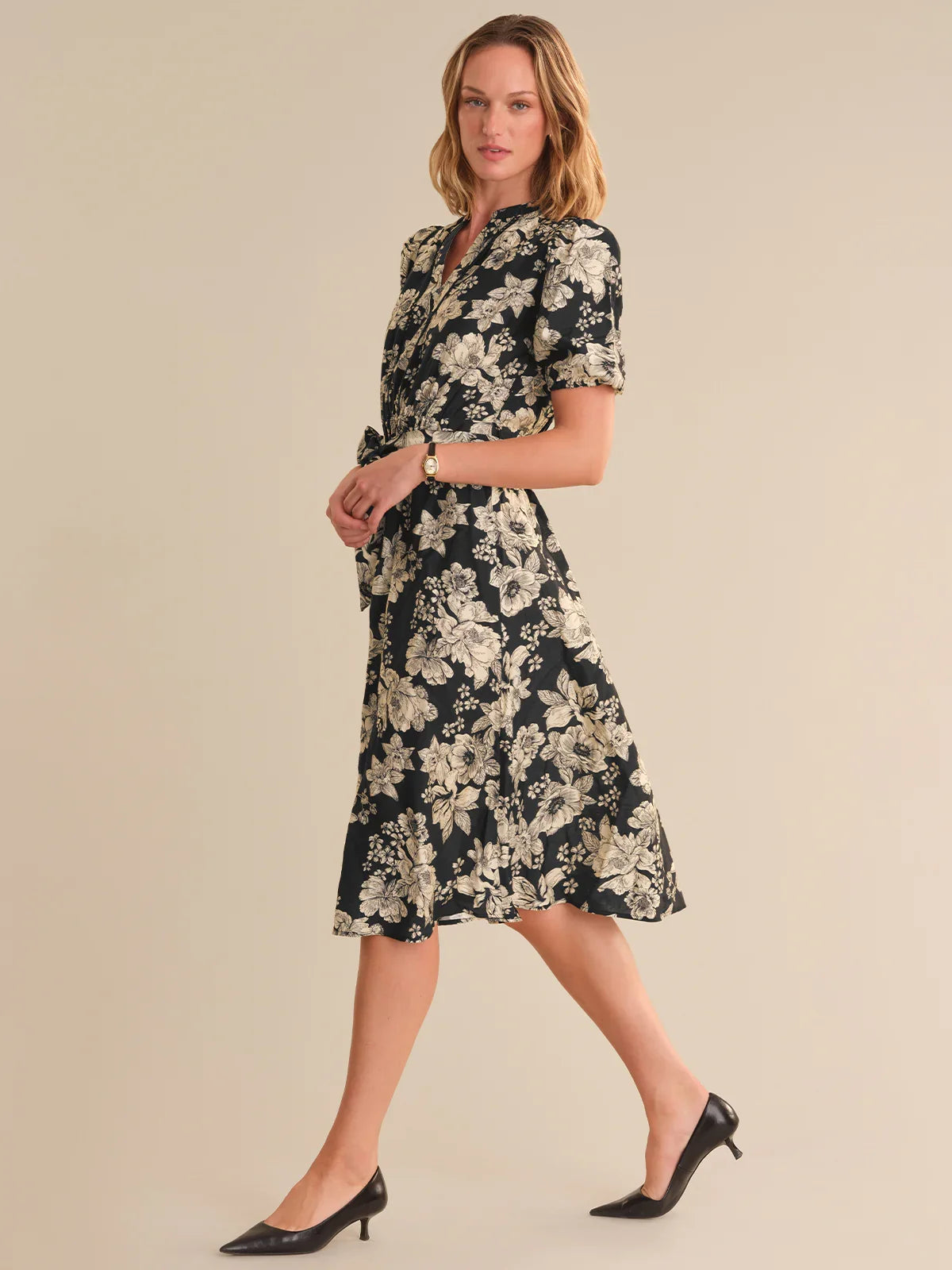 Woman wearing a black floral dress on a beige background