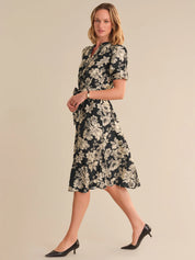 Woman wearing a black floral dress on a beige background