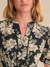 Woman wearing a black floral blouse with a neutral background