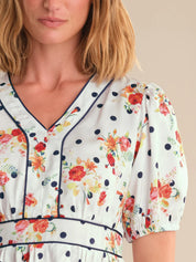 Woman wearing a floral dress with polka dot trim on a beige background