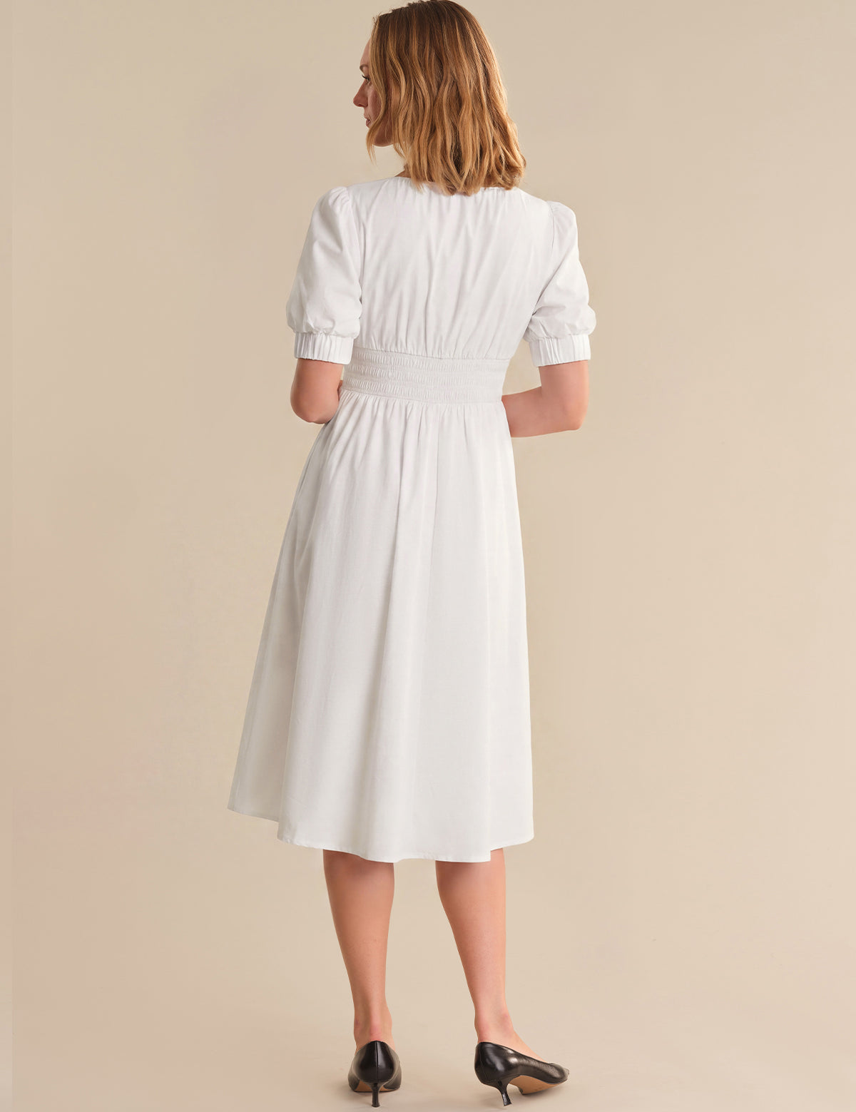 Woman wearing a white dress against a beige background