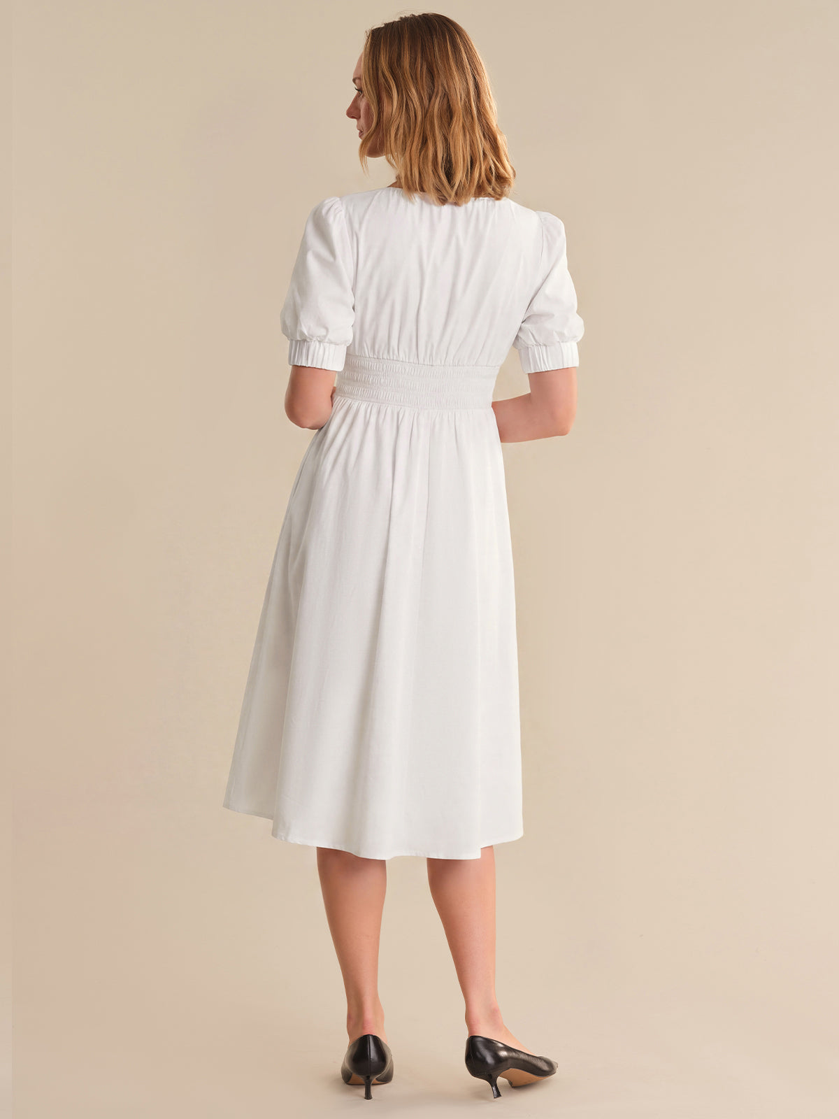 Woman wearing a white dress against a beige background