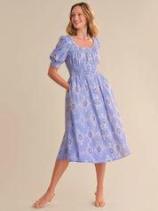 Woman wearing a blue patterned dress on a beige background