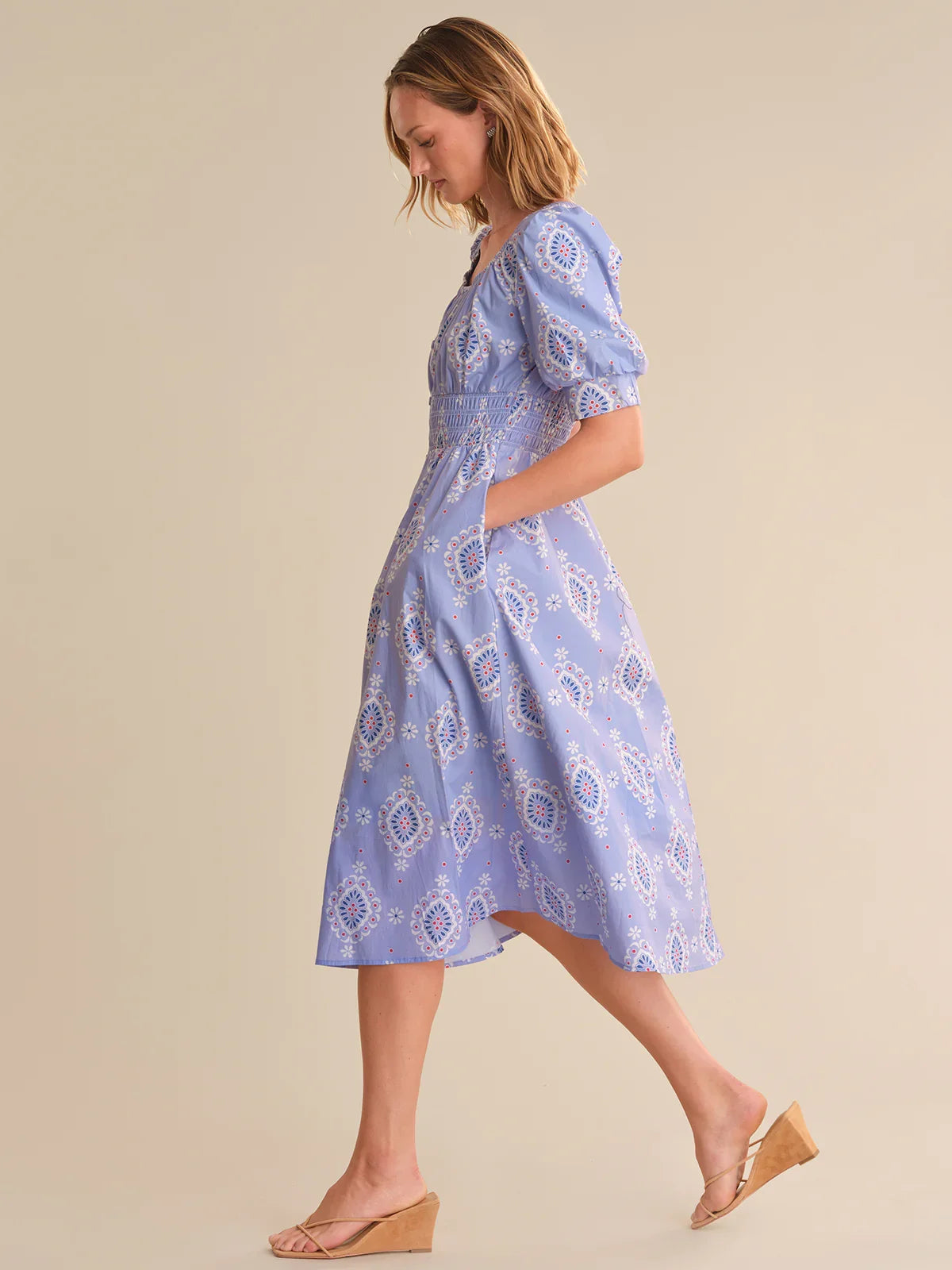 Woman wearing a blue patterned dress on a beige background