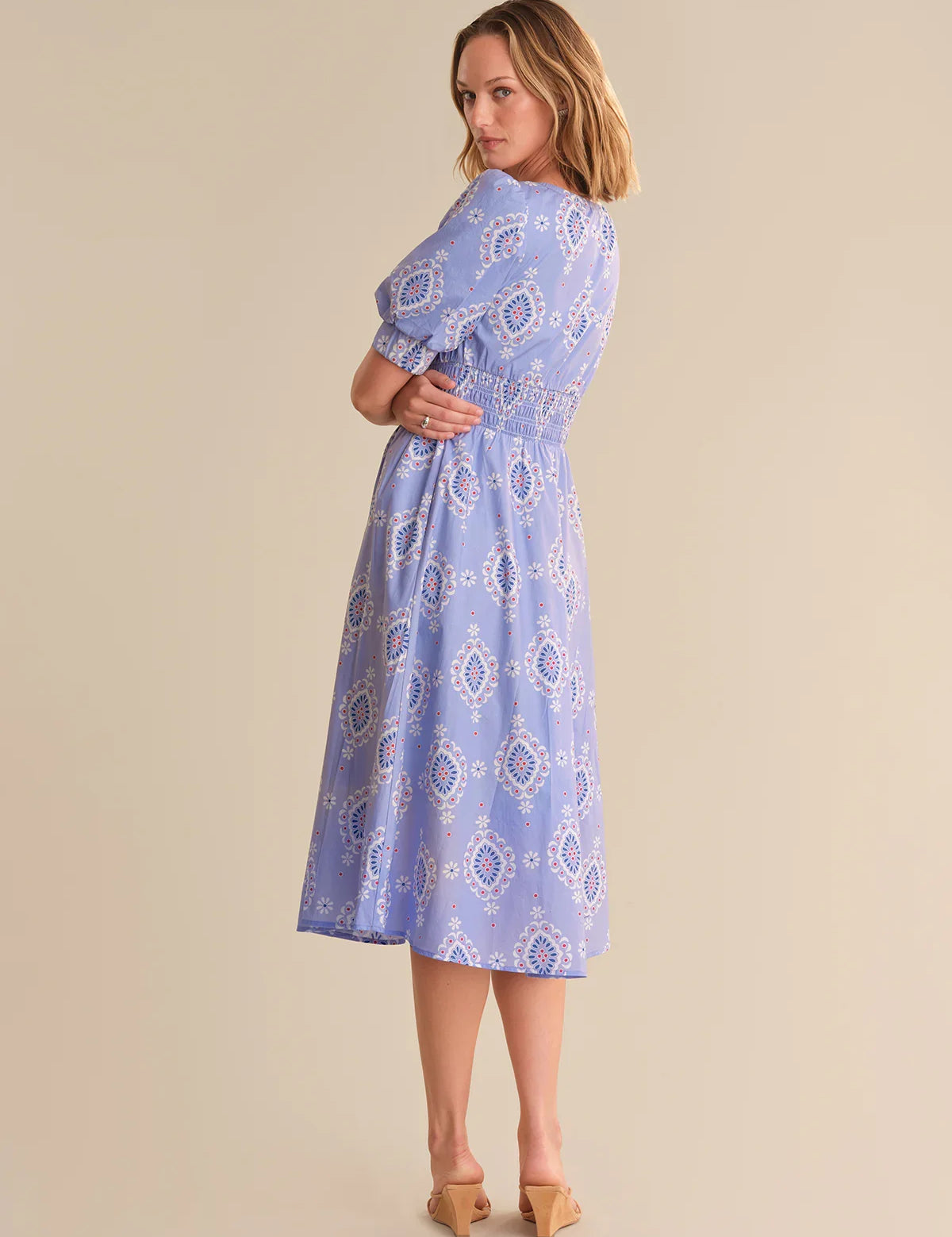 Woman wearing a blue patterned dress against a beige background