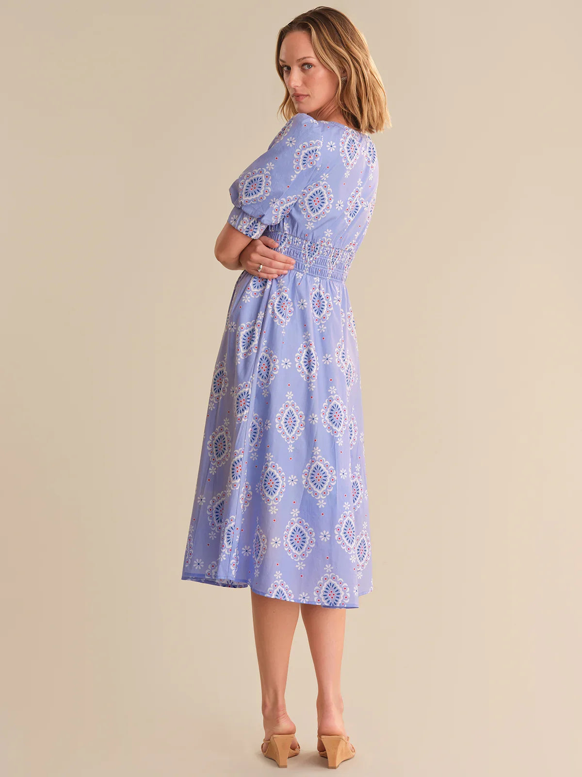 Woman wearing a blue patterned dress against a beige background