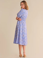 Woman wearing a blue patterned dress against a beige background