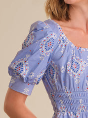 Close-up of a blue patterned dress with puff sleeves on a beige background