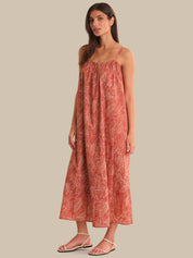 Woman wearing a red patterned dress on a beige background