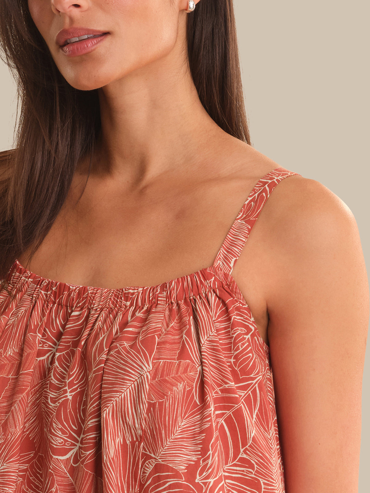 Woman wearing a red floral dress with thin straps against a neutral background