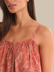 Woman wearing a red floral dress with thin straps against a neutral background
