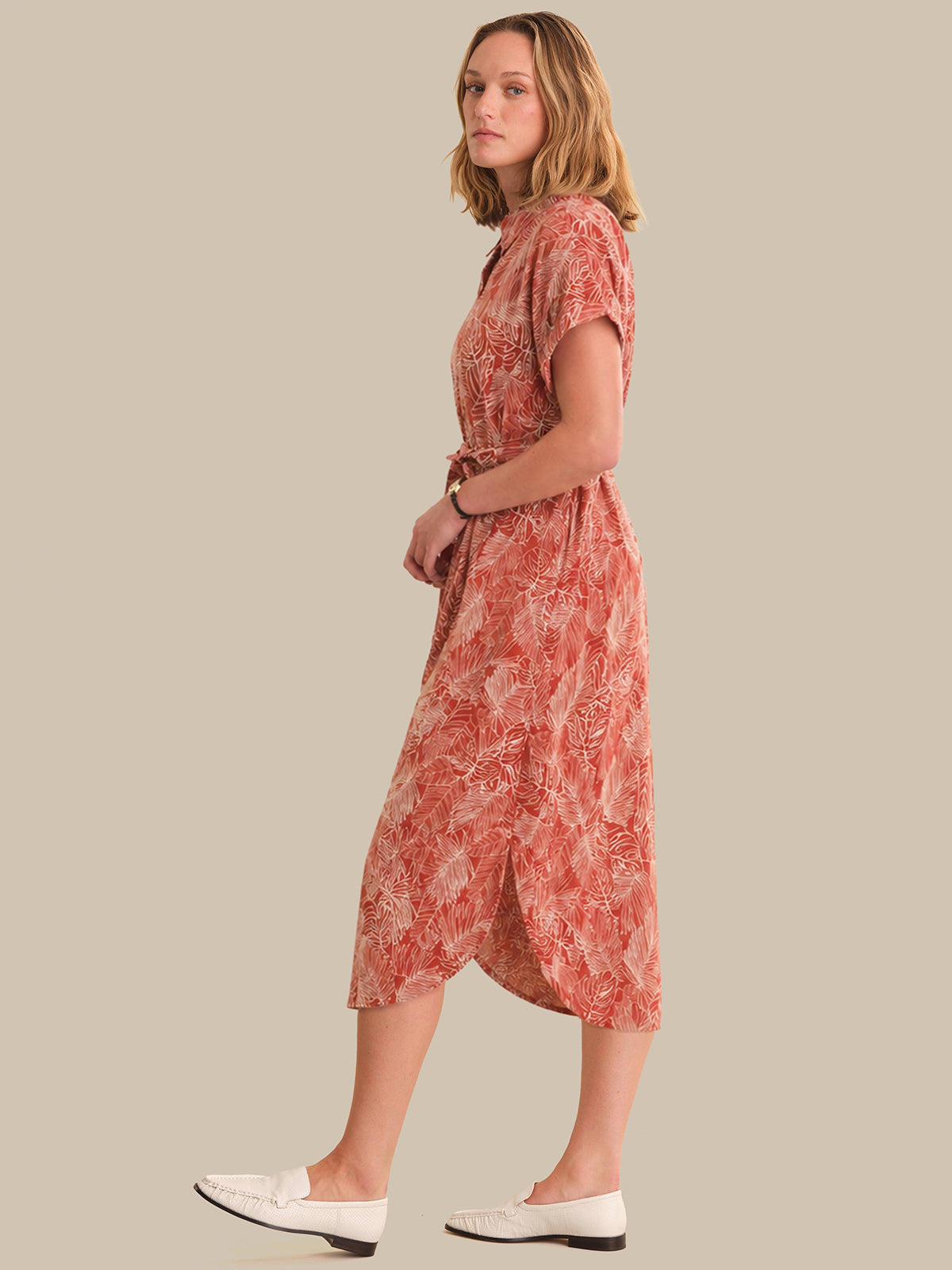 Woman wearing a red patterned dress on a beige background