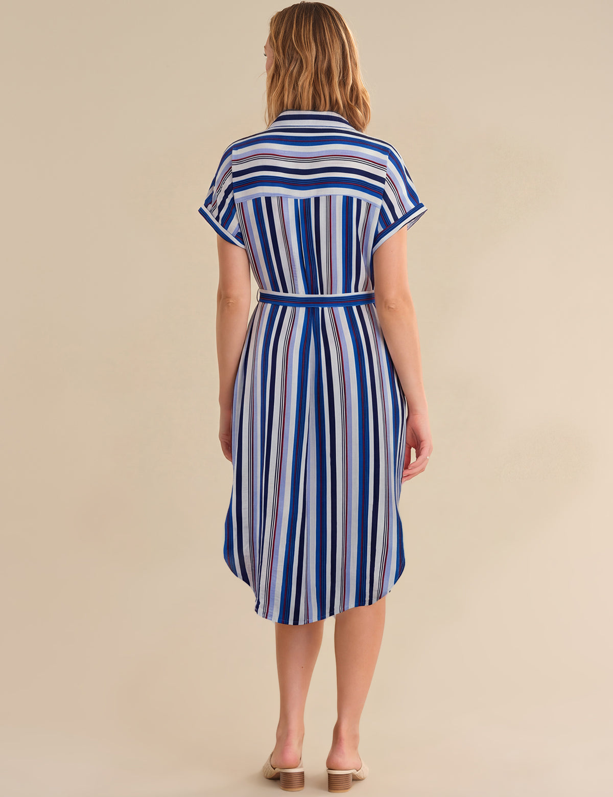 Woman wearing a blue and white striped dress on a beige background