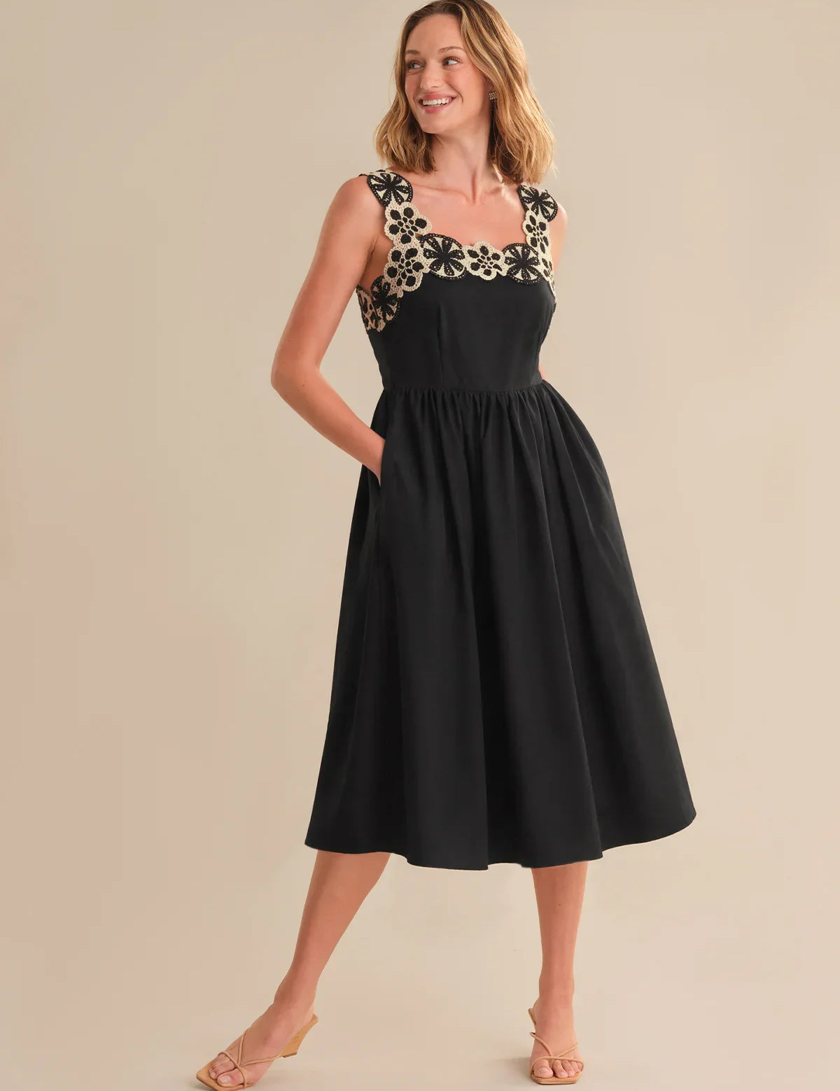 Woman wearing a black dress with floral embellishments on a beige background