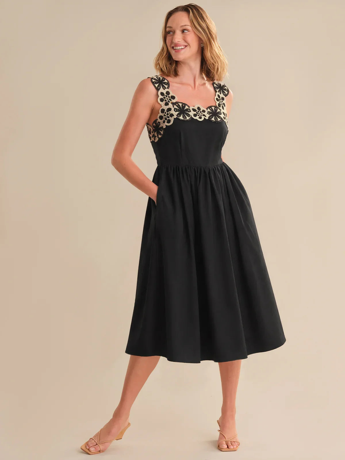 Woman wearing a black dress with floral embellishments on a beige background