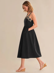 Woman wearing a black dress with floral embellishments on a beige background