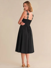 Woman wearing a black dress with floral straps on a beige background