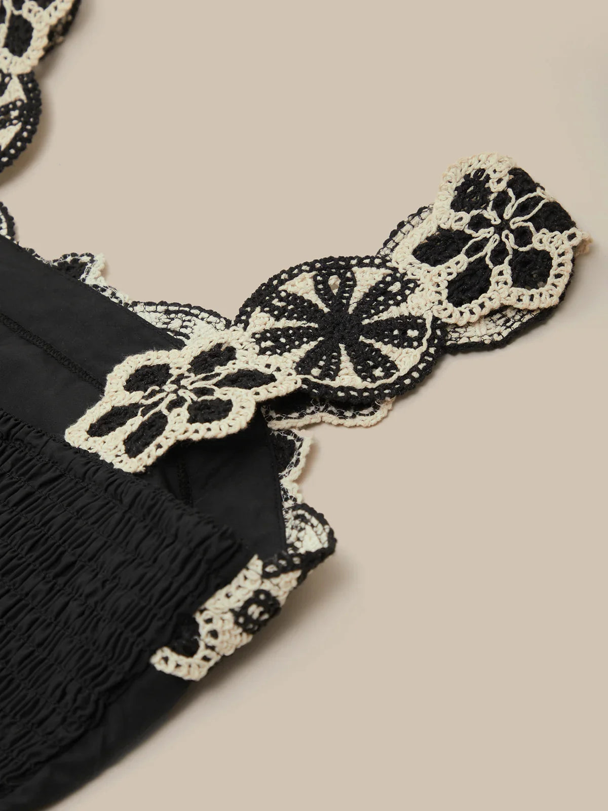 Black fabric with white lace trim on a beige background