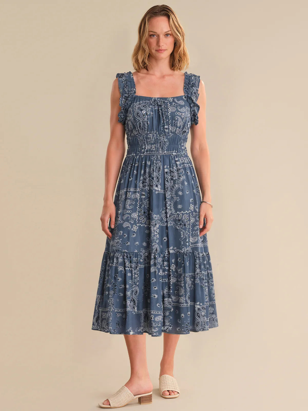 Woman wearing a blue patterned dress against a beige background