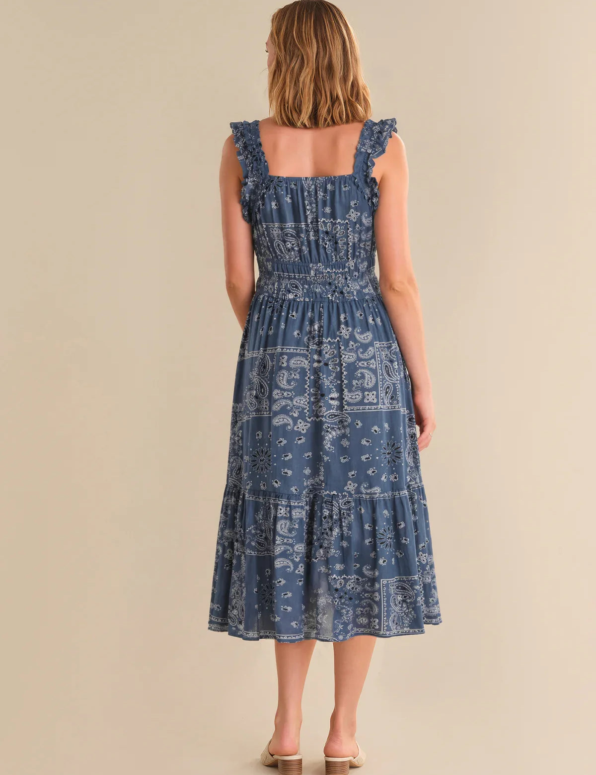 Woman wearing a blue patterned dress on a beige background