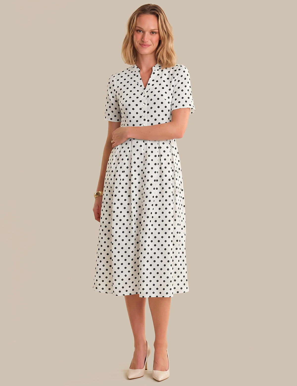 Woman wearing a polka dot dress on a beige background