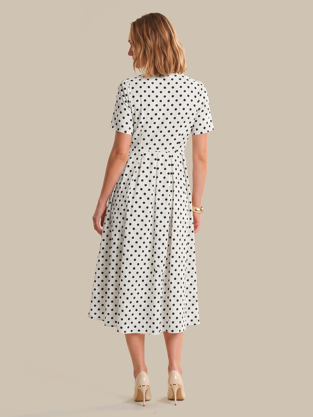 Woman wearing a polka dot dress on a beige background