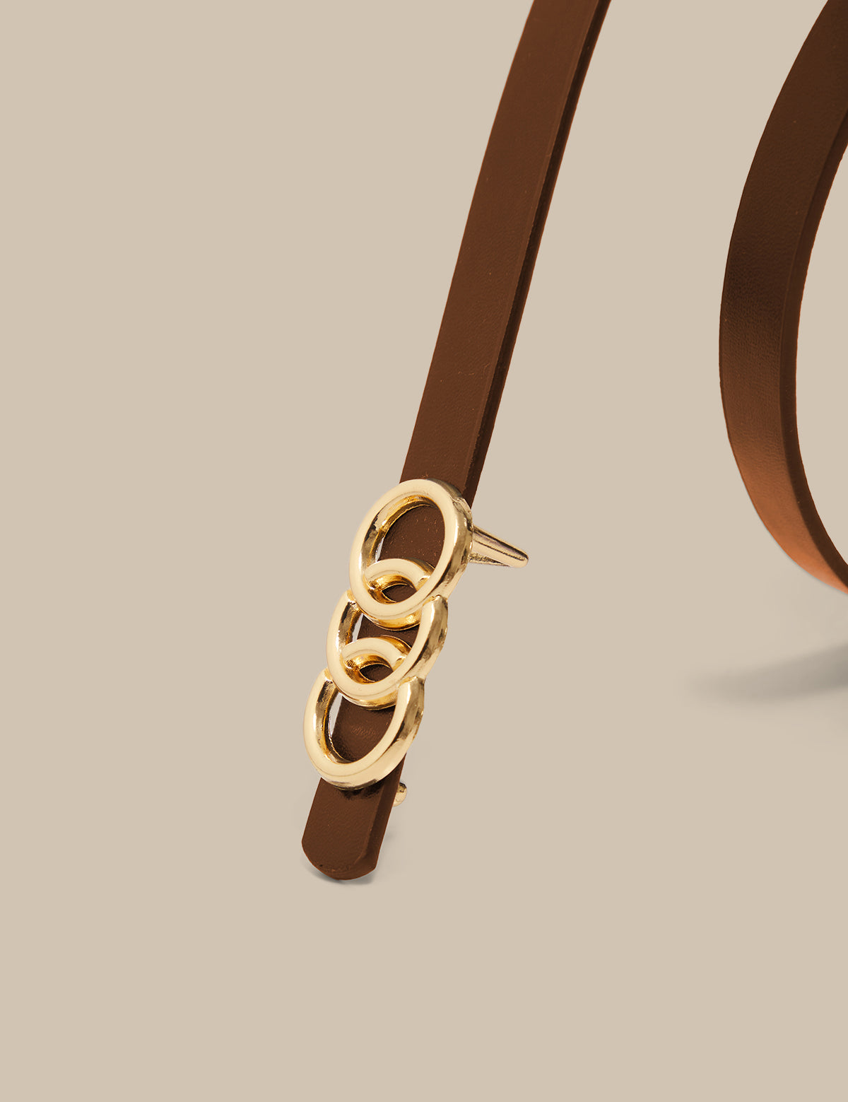 Brown belt with gold buckle on a beige background