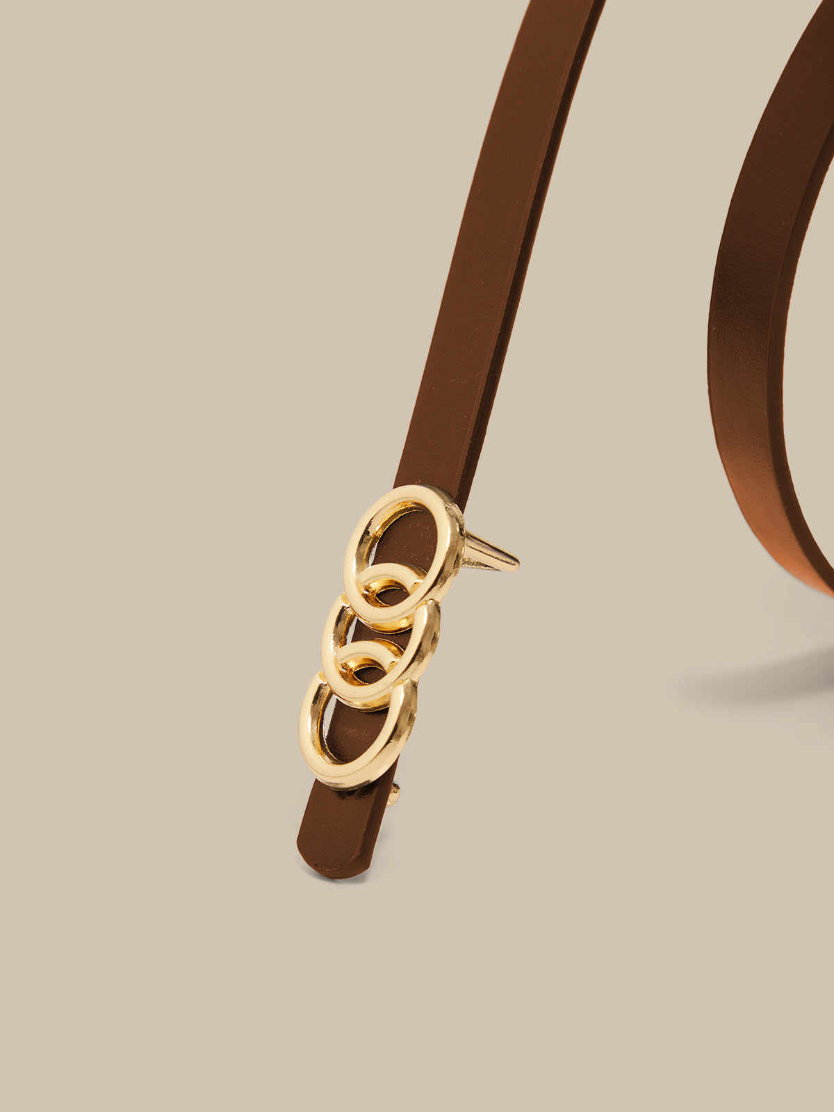 Brown belt with gold buckle on a beige background