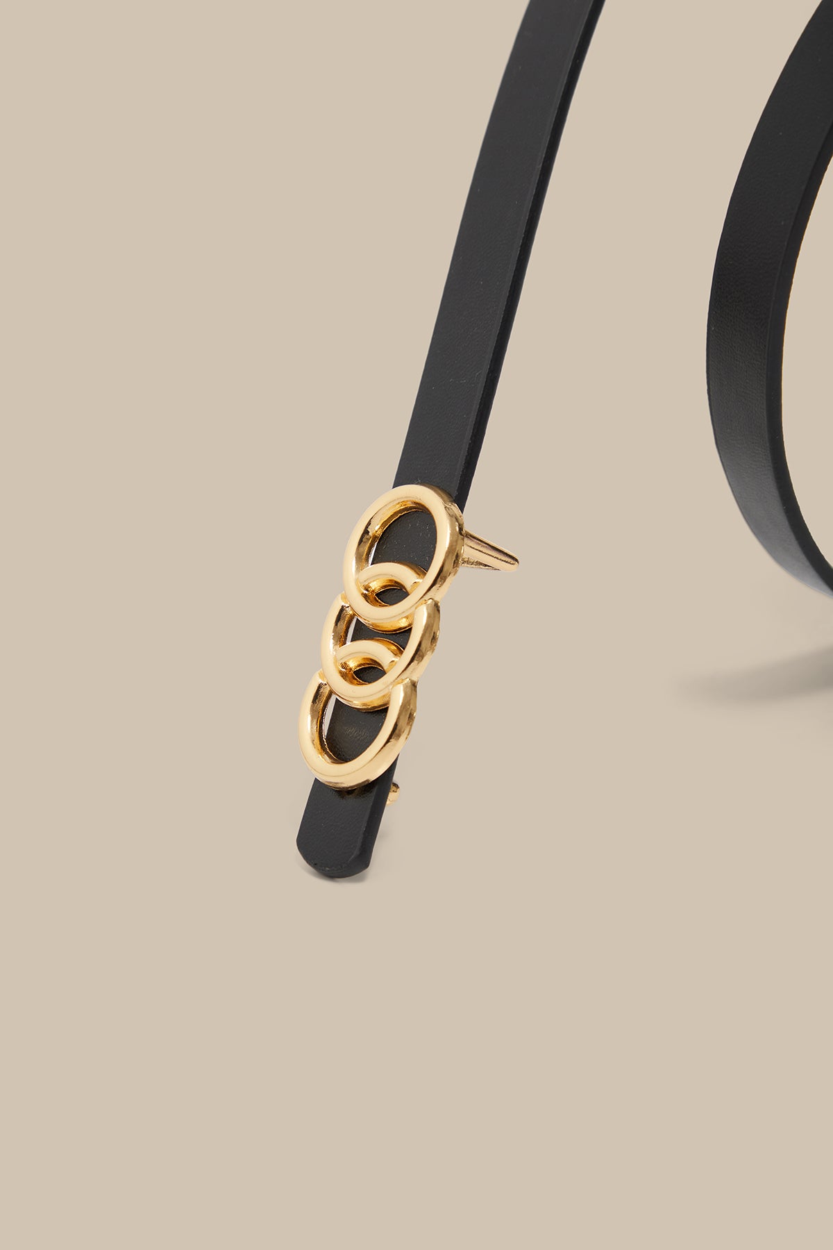 Black belt with a gold buckle on a beige background