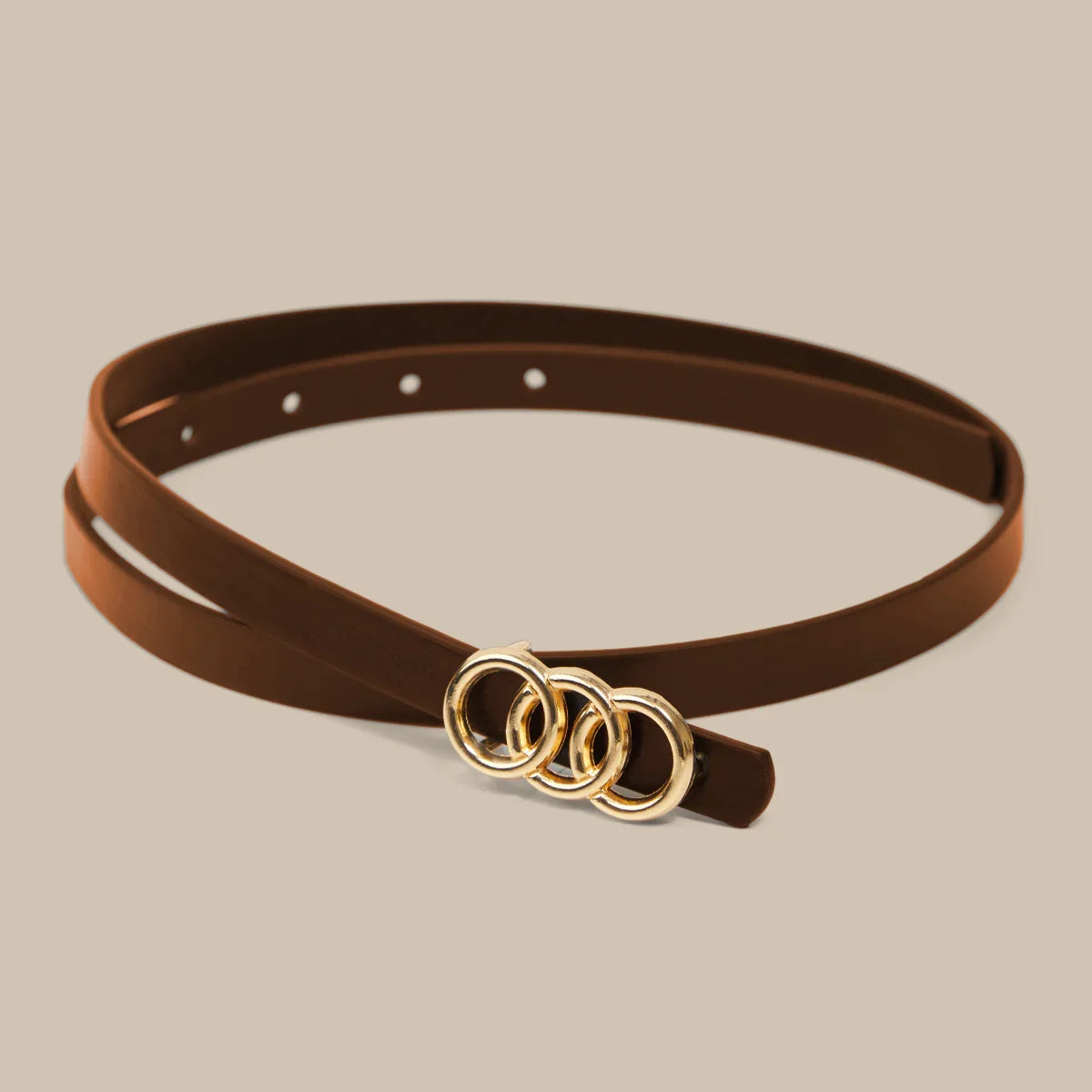 Brown belt with gold rings on a beige background